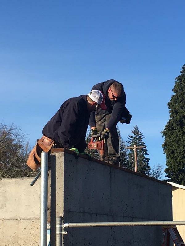 Two guys on cement structure drilling