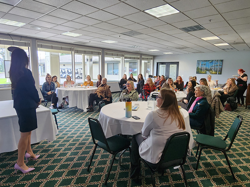 Ladies meeting at an event, sitting around round tables, with a speaker talking
